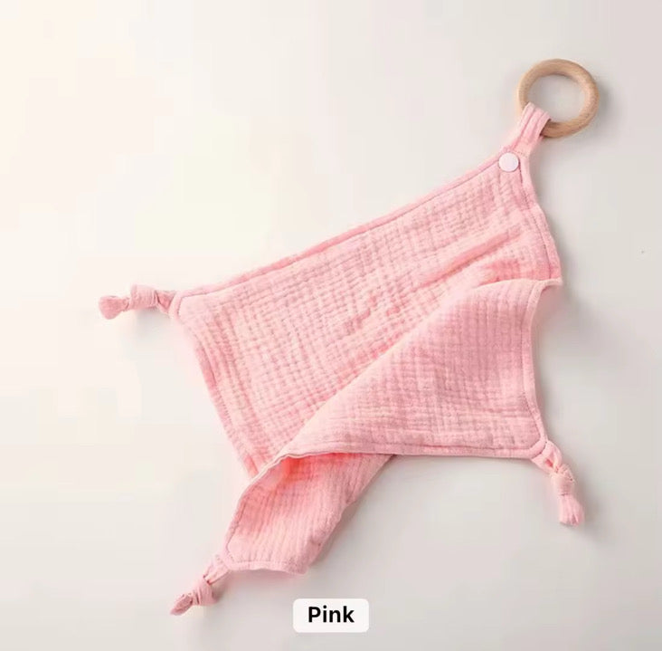 Pink muslin comforter with wooden teether ring, perfect for soothing, snuggling, and teething relief.