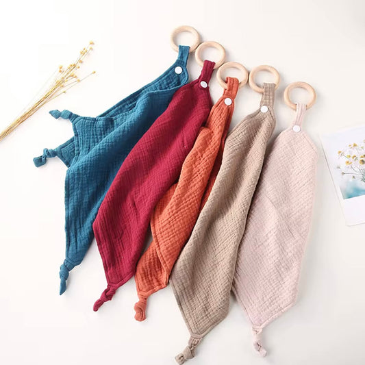 Set of five muslin comforters with wooden teethers in teal, wine, rust, taupe, and beige for soothing and snuggles.