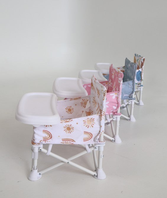 Baby standing next to portable baby chairs