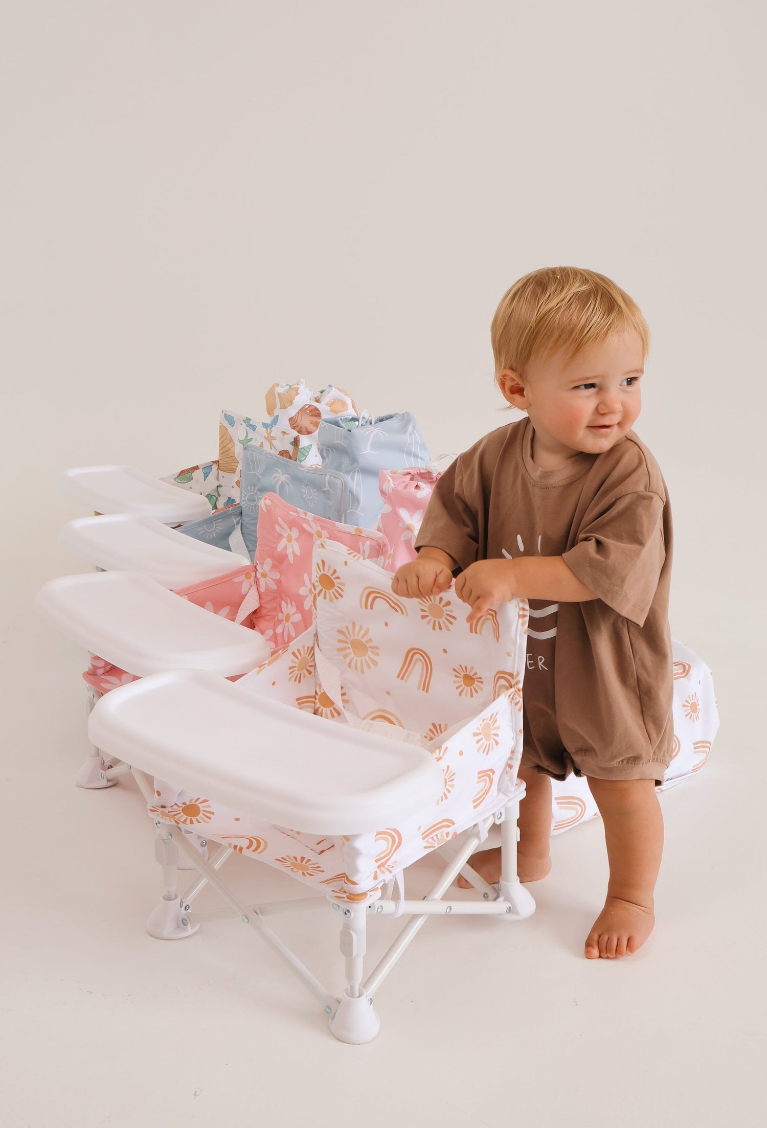 Baby standing next to portable baby chairs