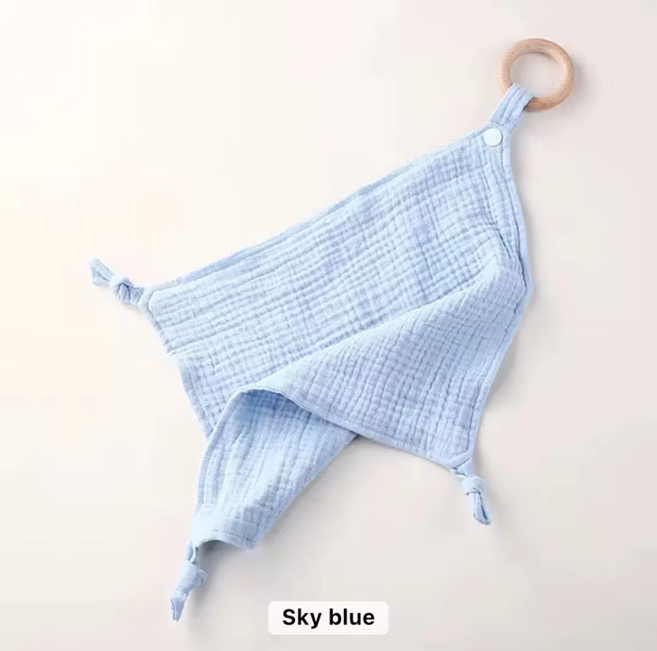 Sky-blue muslin comforter with natural wooden teething ring, soft and gentle on baby’s skin.