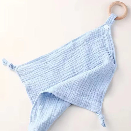 Sky-blue muslin comforter with natural wooden teething ring, soft and gentle on baby’s skin.