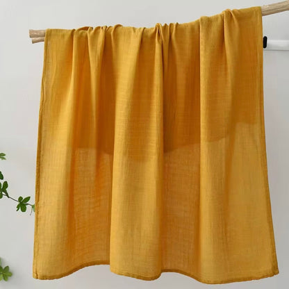 Mustard yellow muslin baby wrap, warm-toned, lightweight, and cozy for babies.