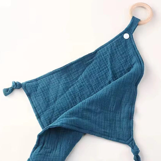 Dark blue muslin comforter with wooden teething ring, soothing and gentle on baby’s skin.