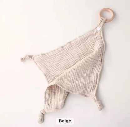 Beige muslin comforter with wooden teether ring, breathable and gentle for newborns and toddlers.”