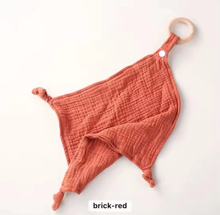 Brick-red muslin comforter with wooden teether, soft and lightweight design for newborns and toddlers.