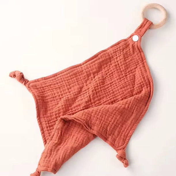 Brick-red muslin comforter with wooden teether, soft and lightweight design for newborns and toddlers.