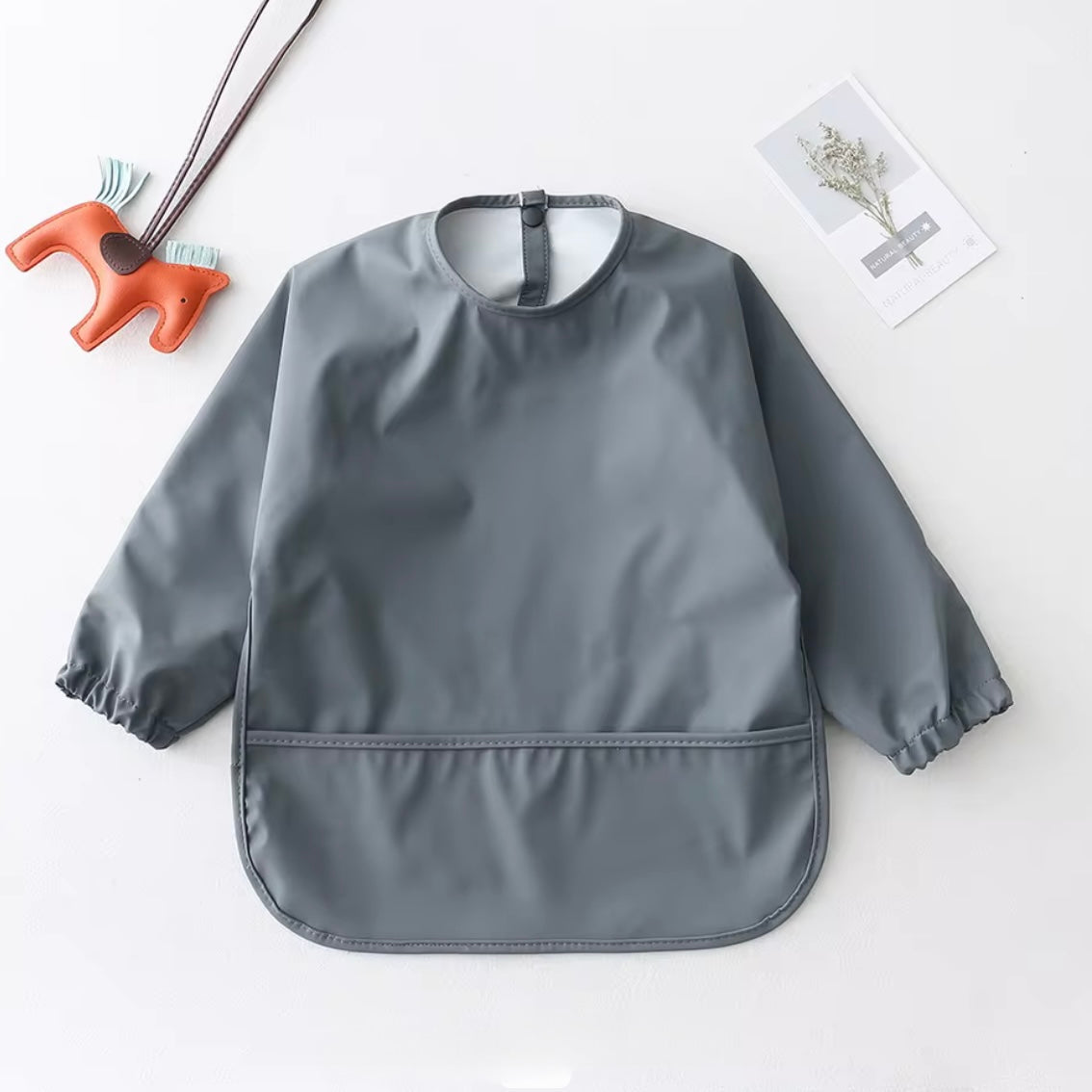 Waterproof sleeved smock bib in dark grey with elastic cuffs and pocket.