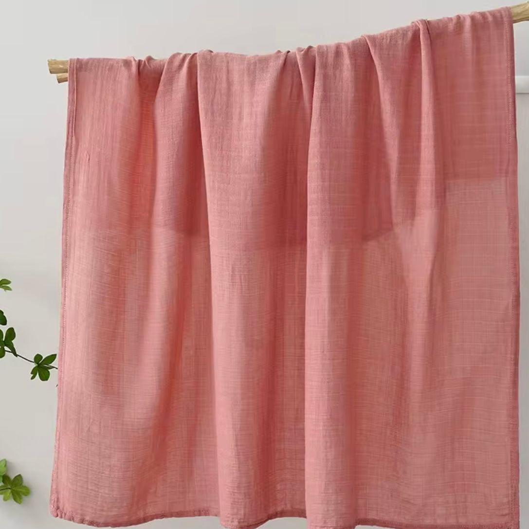 Soft coral muslin baby wrap, lightweight, cozy, and perfect for baby swaddling.