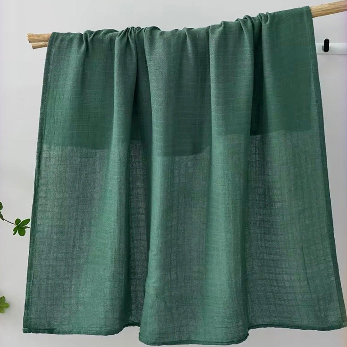 Forest green muslin baby wrap, extra-soft and breathable for newborn comfort.