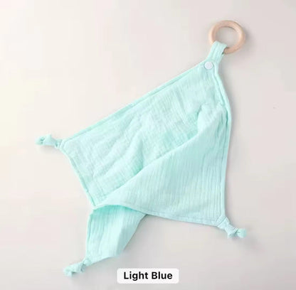 Light blue muslin comforter with natural wooden teether ring, soft and breathable for babies and toddlers.