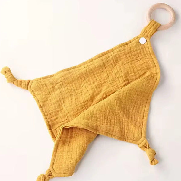 Mustard yellow muslin comforter with wooden teether ring, breathable fabric for baby soothing and sensory play.