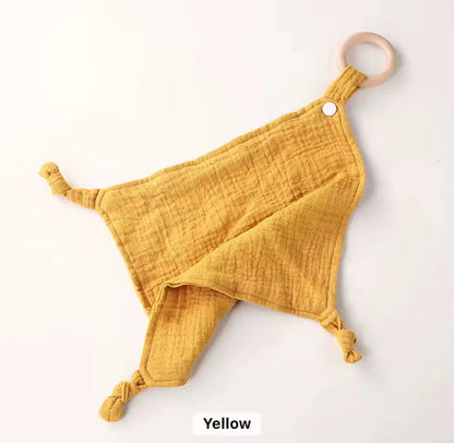 Mustard yellow muslin comforter with wooden teether ring, breathable fabric for baby soothing and sensory play.