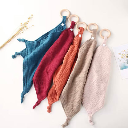 Set of five muslin comforters with wooden teethers in teal, wine, rust, taupe, and beige for soothing and snuggles.