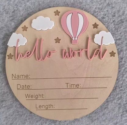 Soft pink hot air balloon hello world plaque – Round milestone plaque with pale pink balloon, engraved birth details, clouds, and stars.